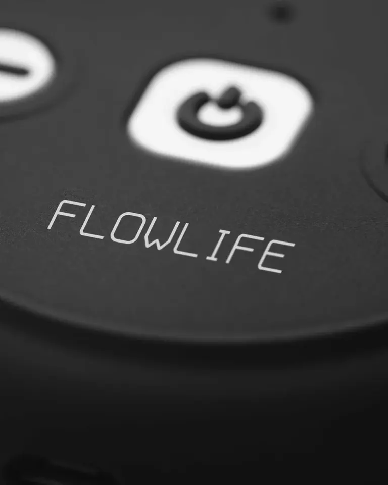 Macro view of the matte black Flowtens Connect showing the white Flowlife logo and minimalist power button.