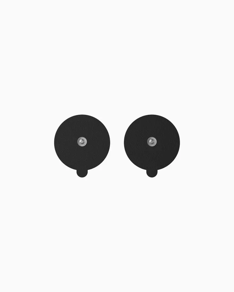 Two round black TENS PADS with silver snap connectors for targeted muscle stimulation and relief with the Flowtens device.