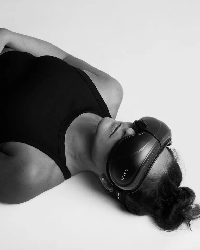 A woman reclined while wearing the black Flowpression Goggles for restorative eye compression therapy.
