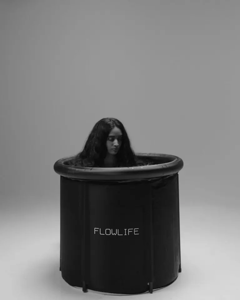 A woman submerged in the black Flowplunge Go portable ice bath for cold therapy and muscle recovery.