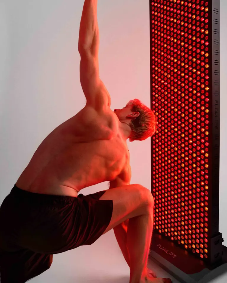Flowlight 4300 Eight Waves panel illuminating a man performing a stretch for full-body muscle recovery.
