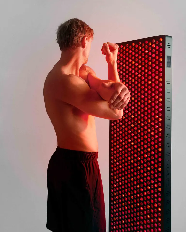 Flowlight 4300 Eight Waves panel providing red light therapy to a man stretching for muscle recovery.