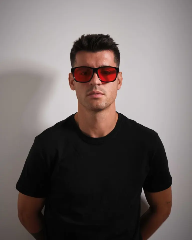 A front-facing portrait of Álvaro Morata wearing black-framed Flowglasses Night Sync 02 - Morata Edition with red lenses.