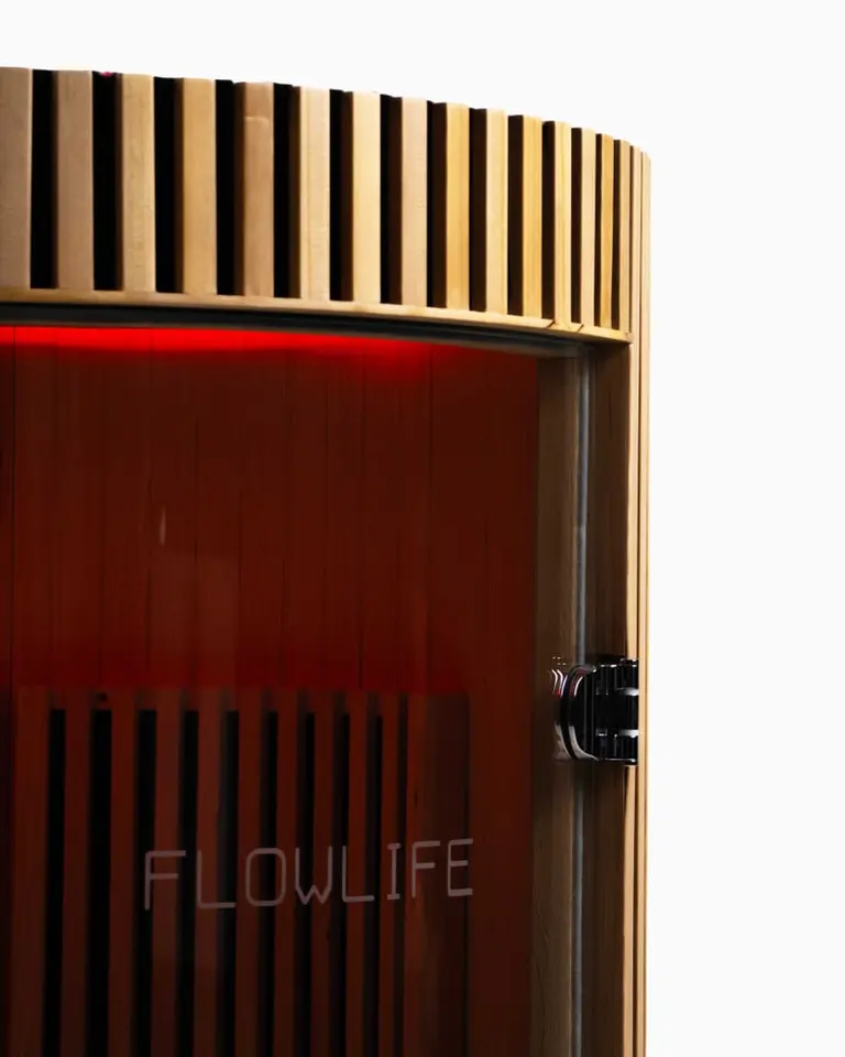 Flowsauna Elite Solo infrared sauna detail showing the hemlock wood slats, red LED lighting, and glass door.