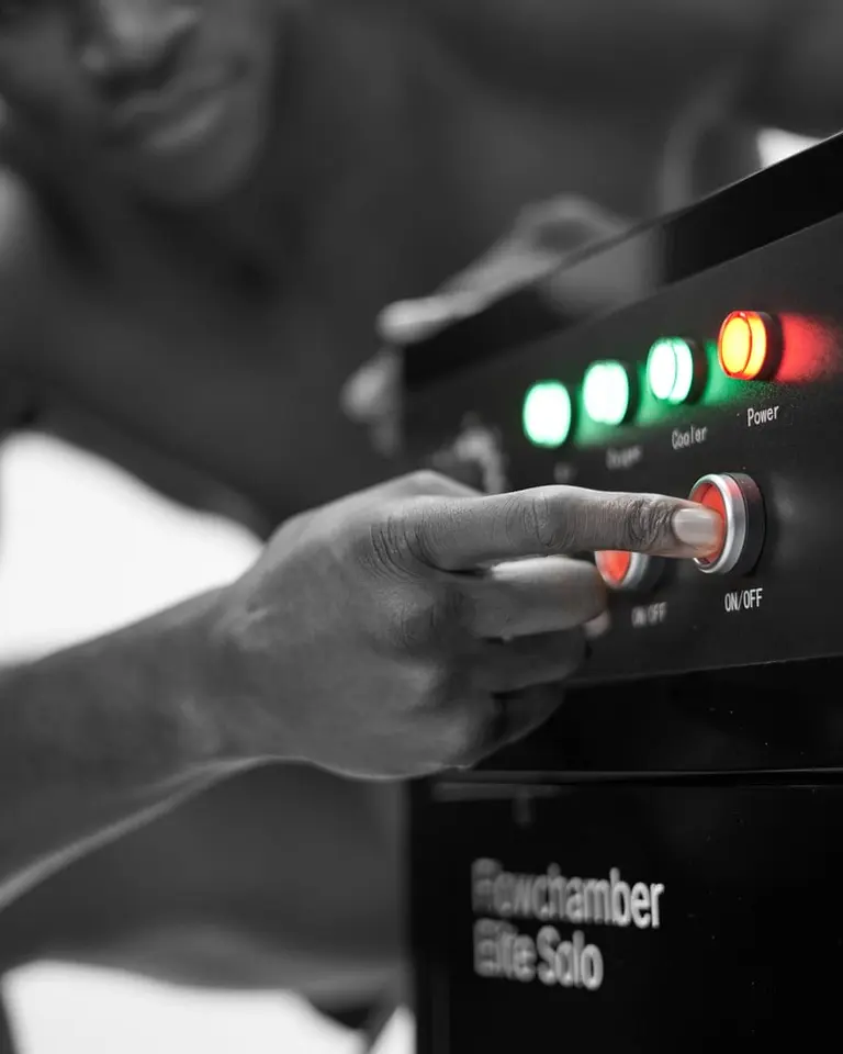 A hand presses the red ON/OFF button on the control panel of the Flowchamber Oxygen Elite 226 Soft-Shell.