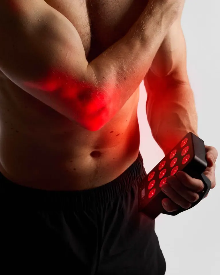 Flowlight Panel Go 60 Two Waves held against an elbow, delivering targeted red light therapy for muscle recovery.