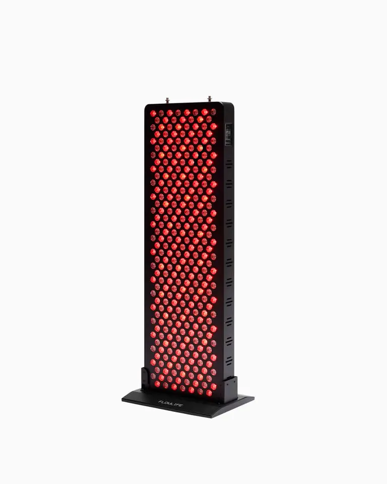 Flowlight Panel 1500 Seven Waves with glowing red LEDs mounted on a black stand for red light therapy sessions.