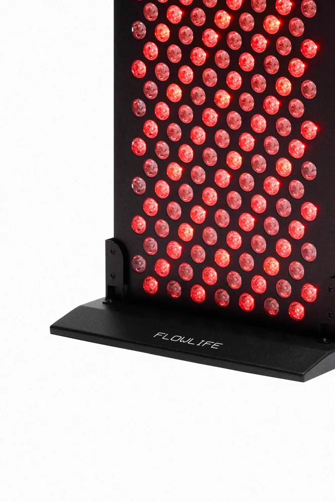 Flowlight 1500 Seven Waves panel with glowing red LEDs and a black floor stand for full-body light therapy.