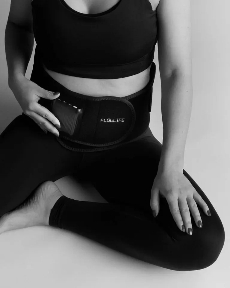 Flowtherma Belt worn by a seated woman for lower back recovery and relief, shown in a black and white usage photo.