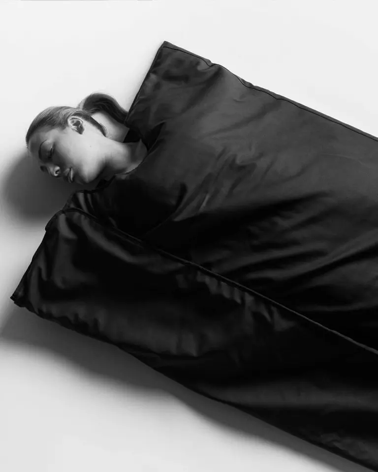 A woman using the black Flowsauna Blanket Pro, an infrared sauna blanket providing deep heat for muscle recovery.
