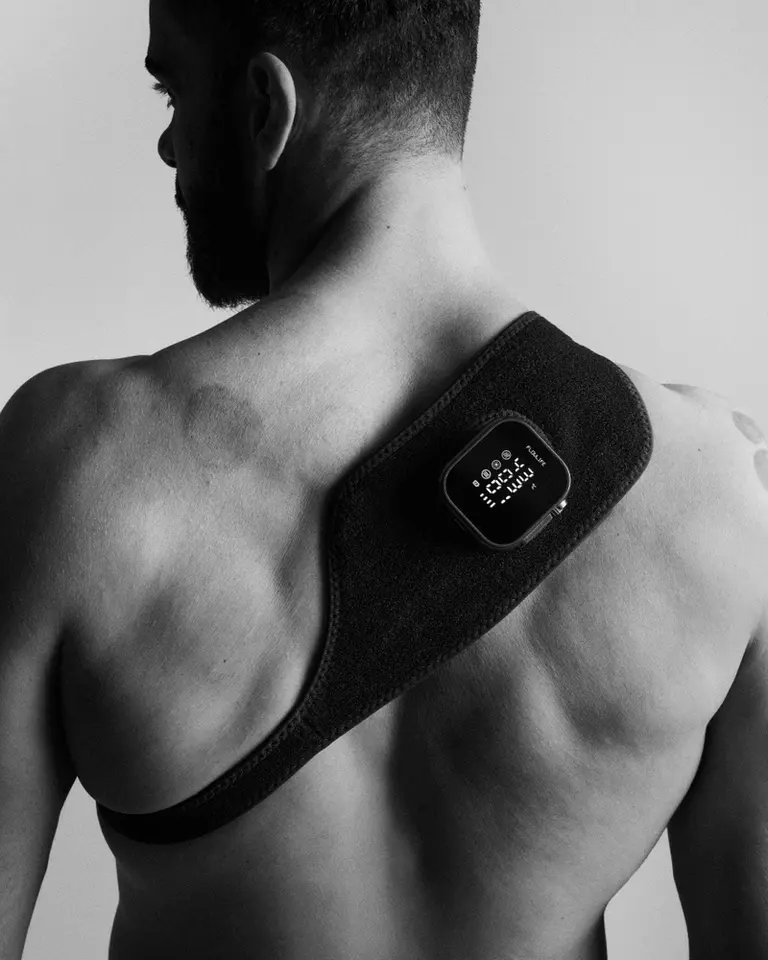 Flowtherma Spot worn on a man’s upper back for targeted heat therapy, captured in a monochrome studio photo.