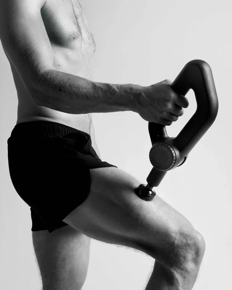 Black Flowgun Ultra with an ergonomic triangular grip being used on the quadriceps to support muscle recovery.
