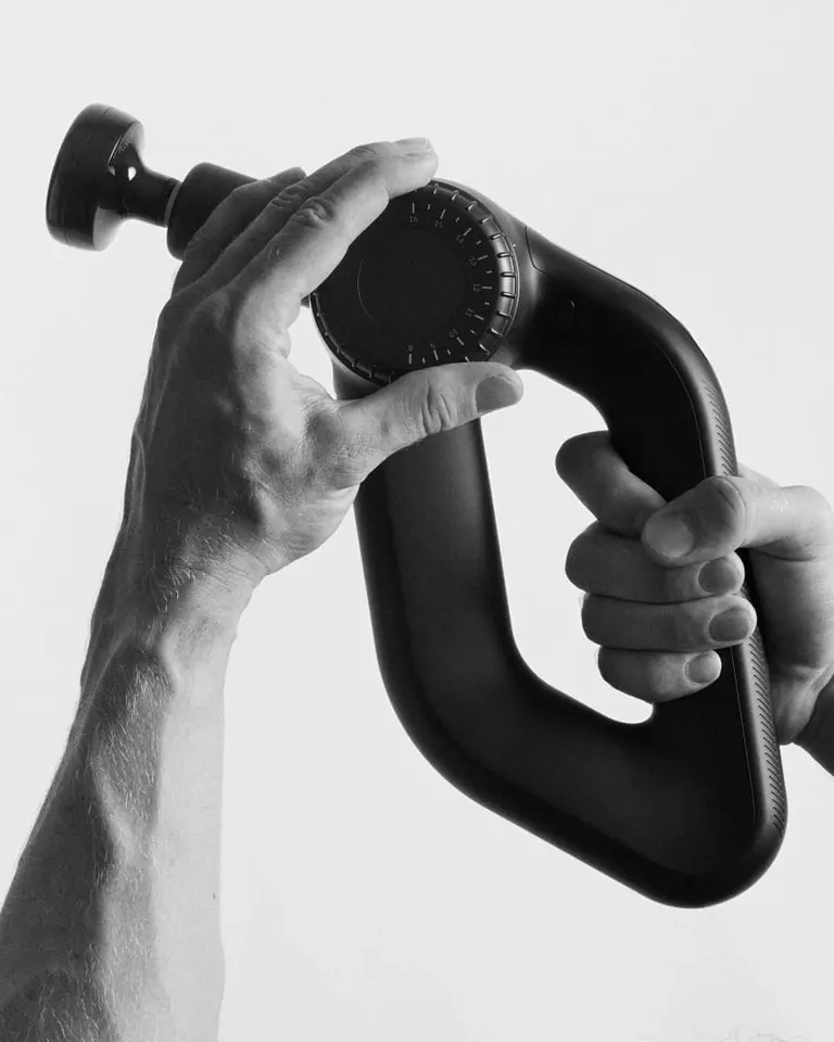 Hands adjusting the dial on a Flowgun Ultra, featuring its ergonomic triangular grip and flat head attachment.