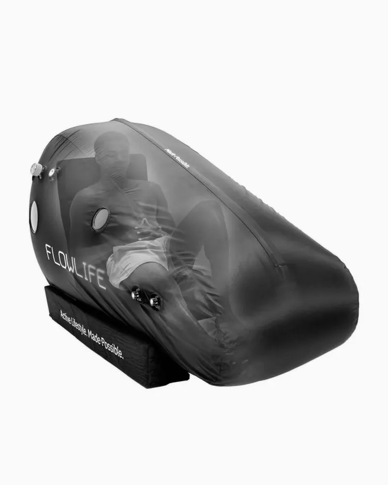 A person reclining inside the black Flowchamber Oxygen Elite 170 Soft-Shell during a mild hyperbaric oxygen therapy session.
