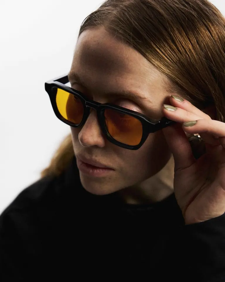 A close-up of a woman wearing the Flowglasses Day Sync 03, showing the amber lenses that filter daytime blue light.