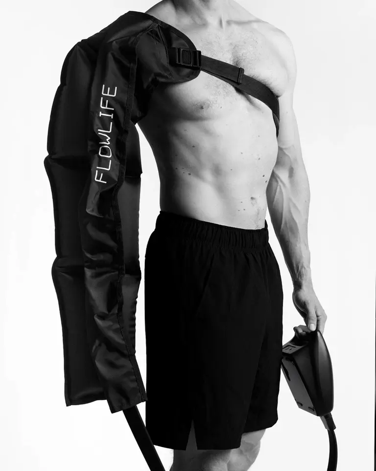 A model wearing the black Pro+ Arm Attachment, a four-chamber compression sleeve secured by an adjustable strap.