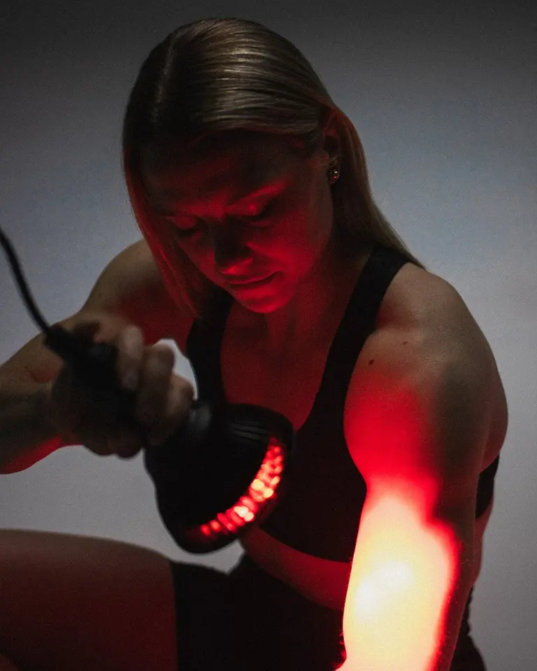 Flowlight Bulb 50 Six Waves emitting red light onto a woman's arm for targeted muscle recovery and circulation.
