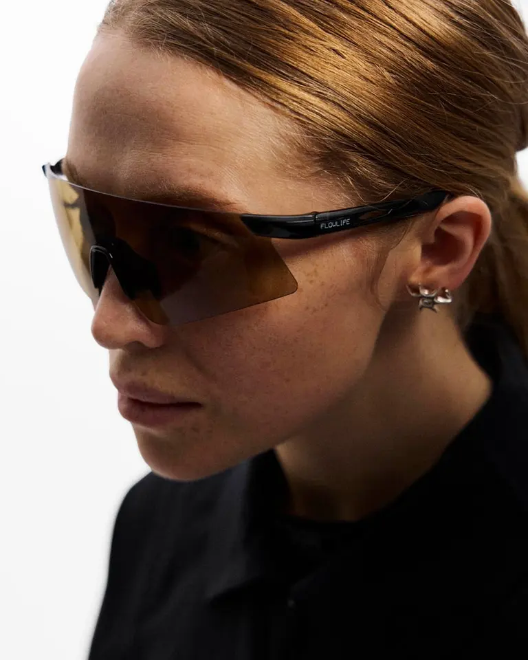 Flowglasses Sport Sync 01 with amber lenses and a black TR90 wraparound frame shown on a model in a side profile.