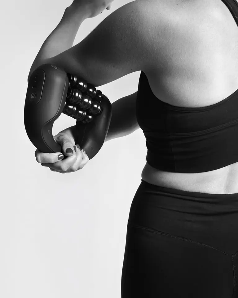 Flowlymph Roller Go being used handheld on the arm in a studio setting for targeted lymphatic drainage.