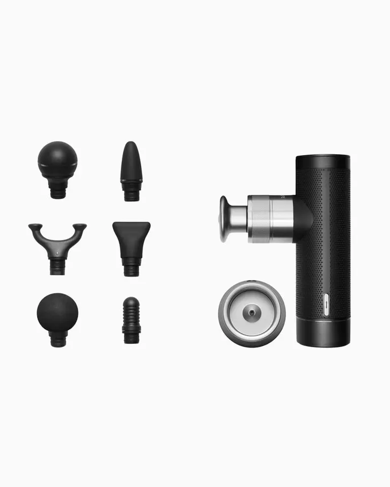 Flowgun ONE massage gun with a textured black aluminum body, silver charging dock, and six interchangeable heads.